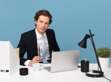 man sitting on chair beside laptop computer and teacup