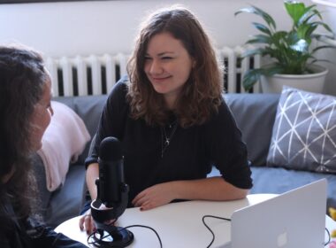 woman in black half-sleeved shirt sitting while facing woman and smiling